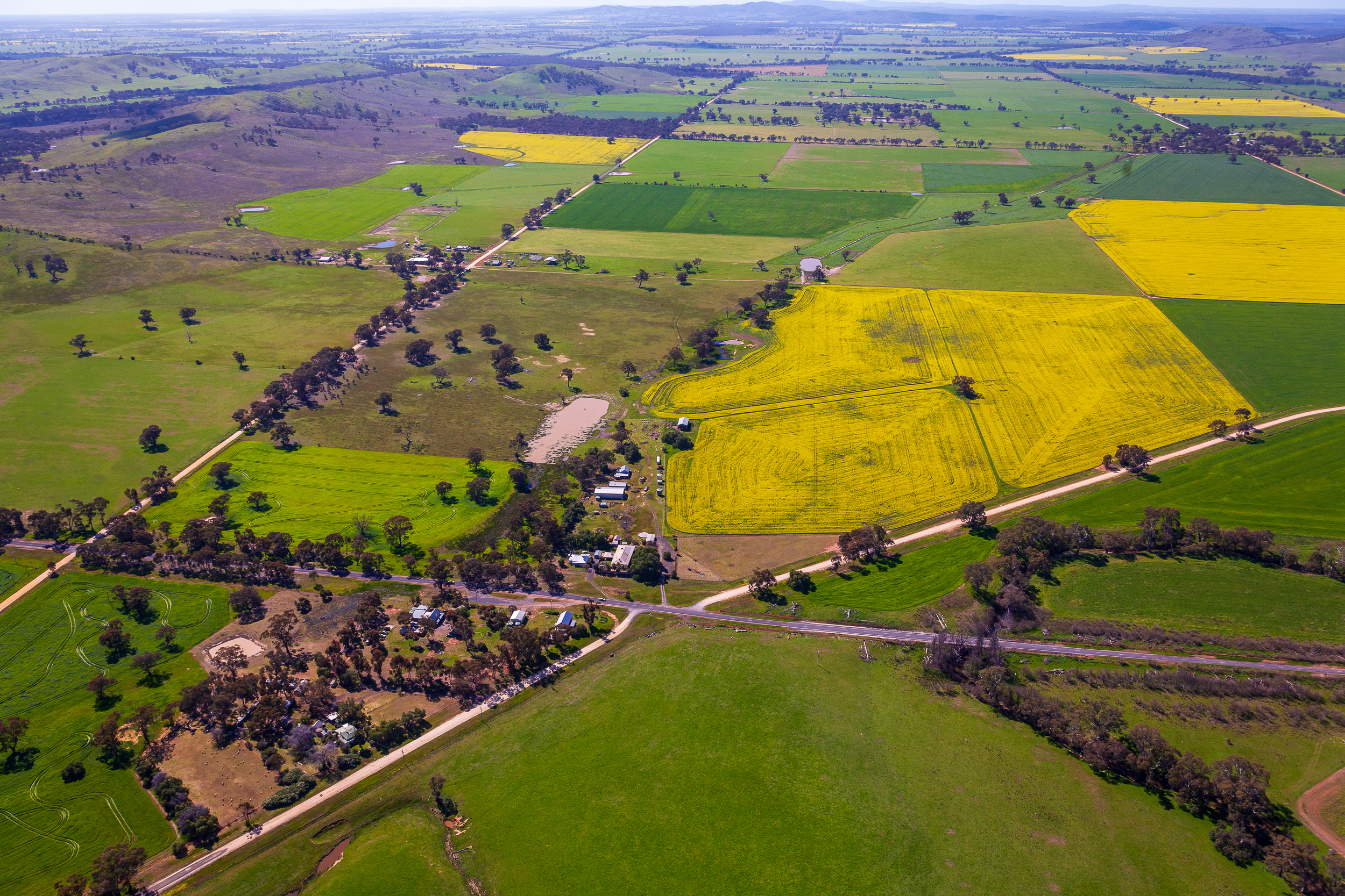 Fixed-wing aerial photography of rural property showing farm buildings, stockyards and surrounding paddocks in Victoria