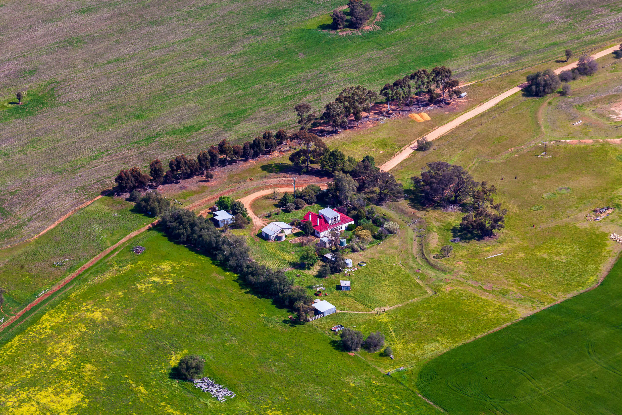 Wide aerial view of mixed farming property in Victoria showing crop rotation paddocks and farm dam