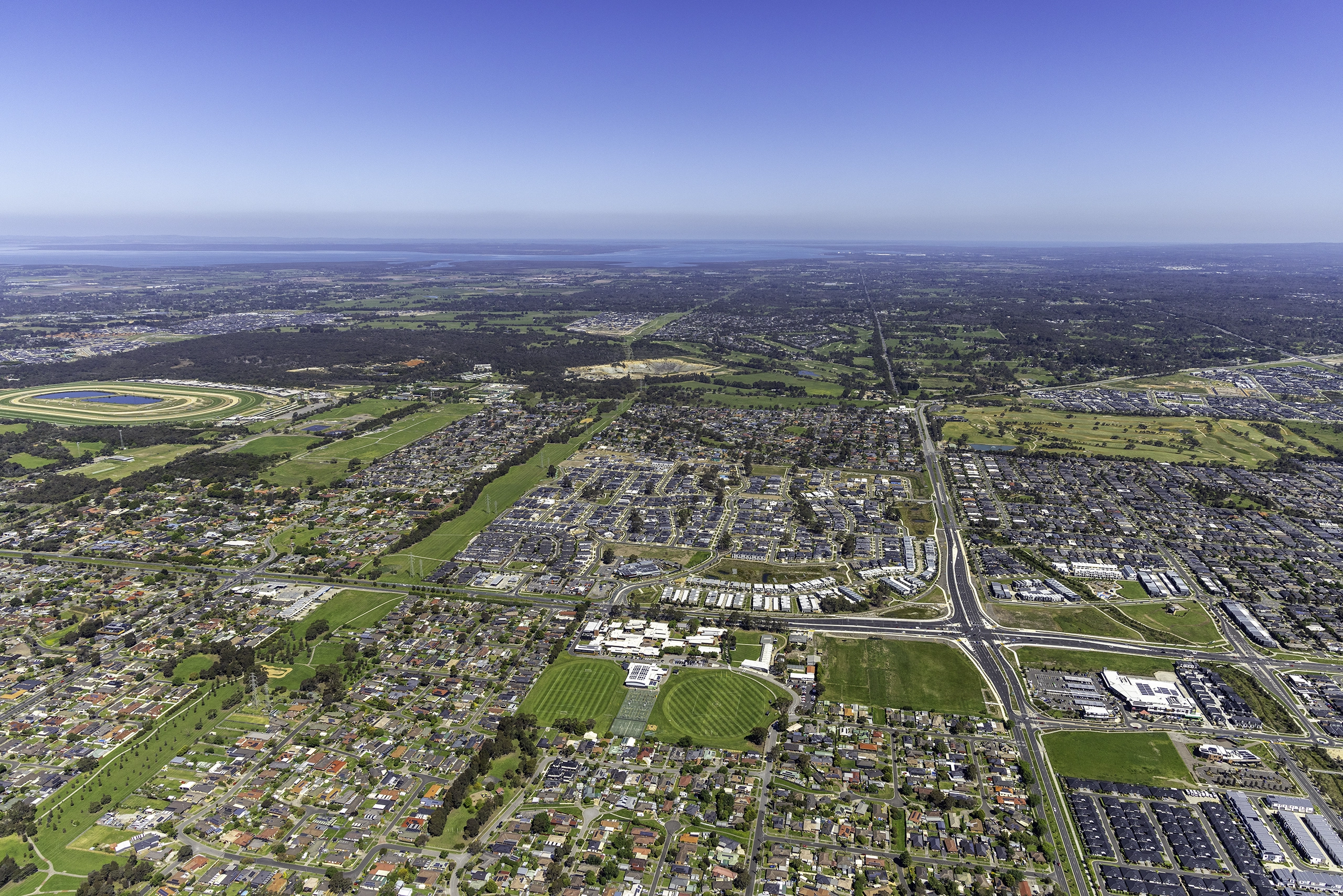 Daytime fixed-wing aerial photography of a new residential community in Clyde North Victoria showing housing development, street layout and surrounding landscape